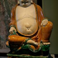 "Stoneware figure of Budai under green and ochre glazes. Henan province, Ming dynasty, dated twenthieth year of Chenghus (AD 1486). OA 1937.1-13.1"