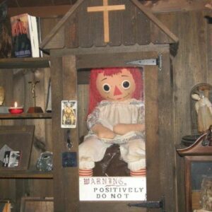 Mythlok - Annabelle real_ Annabelle, the haunted doll, enclosed in a glass case with a sign reading “Positively Do Not"